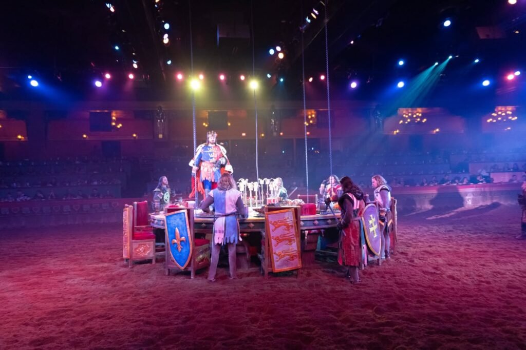 A themed event featuring a table decorated with shields, illuminated by vibrant stage lighting.