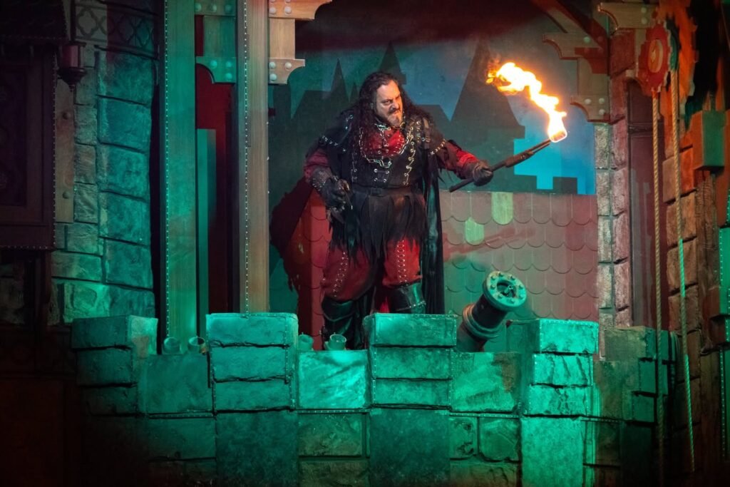 A life-sized figure of a medieval king holding a torch on a castle wall in a haunted house display.