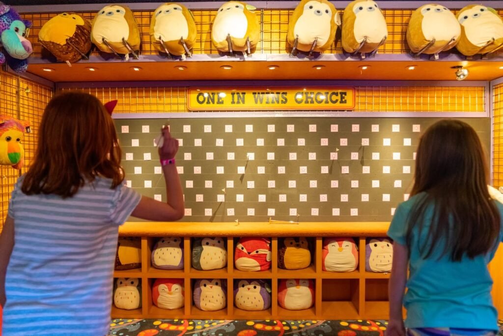 A Sumikko Gurashi plush game with plush mascots on a shelf. A person stands in front of the game.
