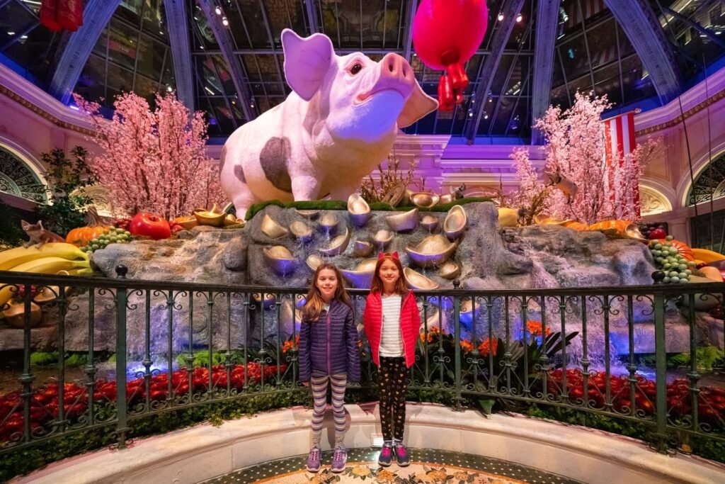 People capture photos with a pink piggy bank and golden eggs at a floral exhibit.
