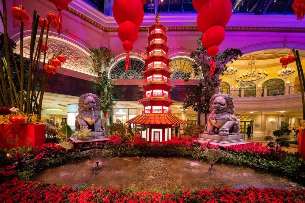 A festive indoor display at the Bellagio featuring red Chinese lanterns, a pagoda, and stone lion statues.