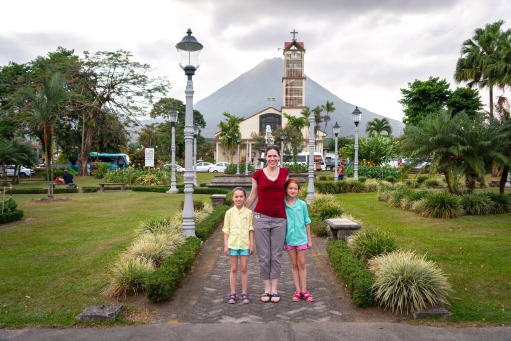 A family walks along a temple path in Pando, with the majestic Pico de Pando volcano rising tall behind them.