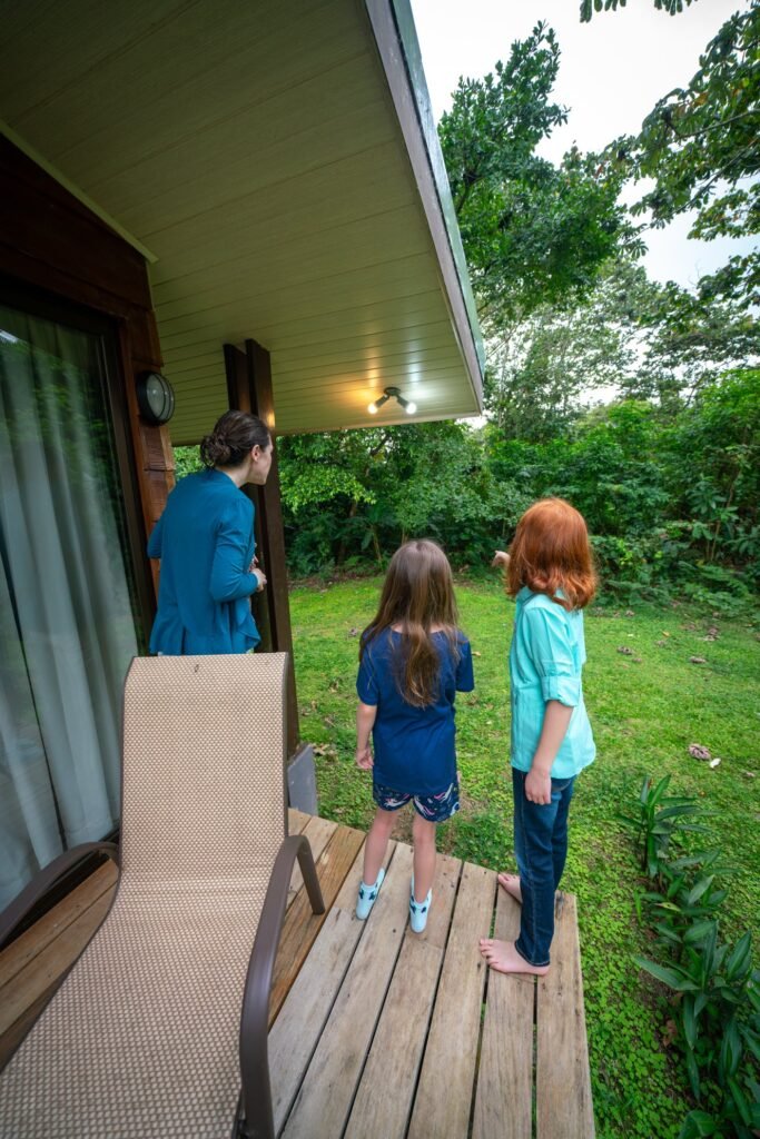 A family enjoys a quiet moment together on a wooden porch surrounded by lush greenery.