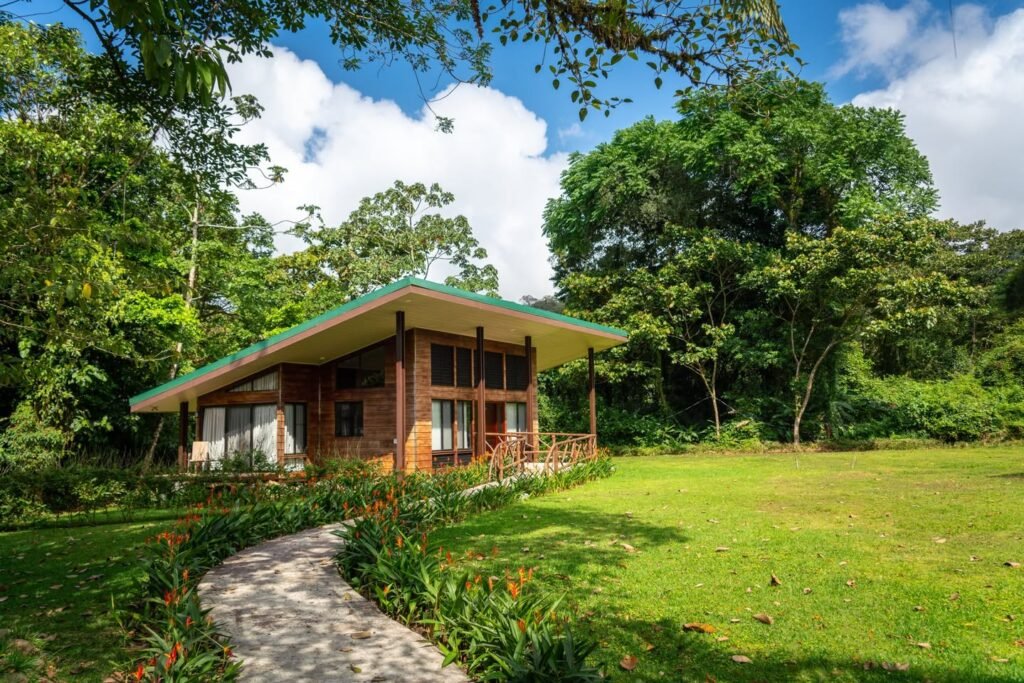 A rustic garden bungalow with lush greenery and a stone pathway.