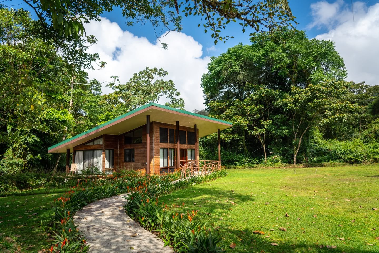 Arenal Nature Villa A rustic garden bungalow with lush greenery and a stone pathway.
