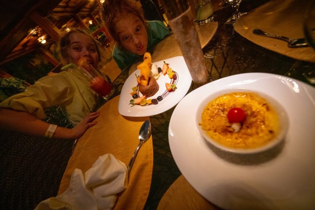 A close-up of plated desserts and a young person smiling in a warm, rustic restaurant setting.