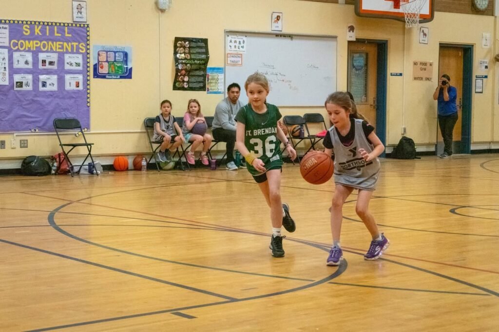 Youth basketball players competing on an indoor court.