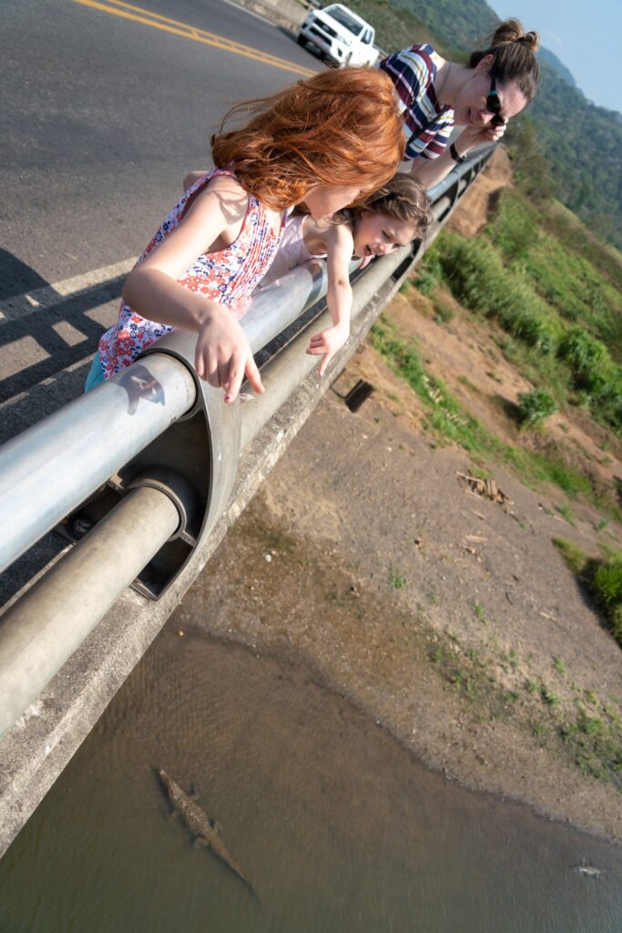 People leaning on a balcony railing to look into a canal.