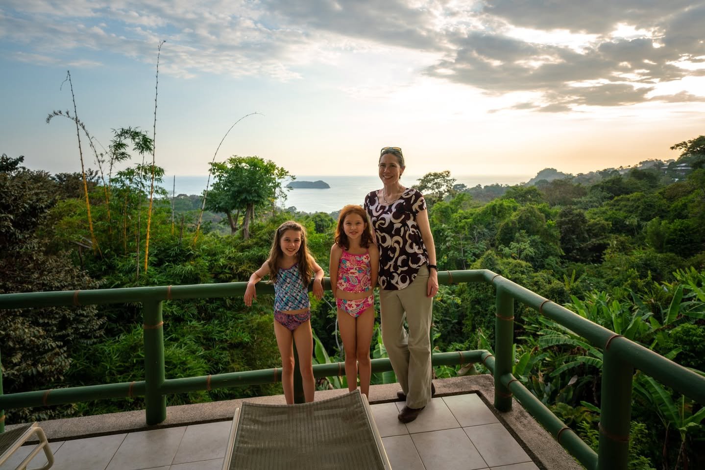 Si Como No A family enjoys a ride on a swing overlooking a lush tropical forest and the ocean from a high vantage point.