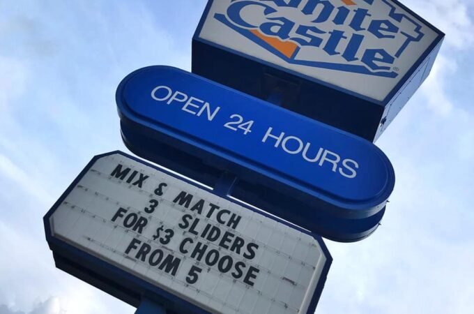 A white and orange White Castle sign against a blue sky with text offering a slider deal.