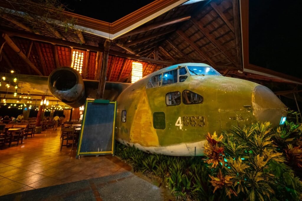 A vintage airplane repurposed as a dining space under a wooden structure at night