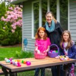 Family members with Easter egg baskets at a wooden picnic table. Brightly colored eggs decorate the table in a sunny garden.
