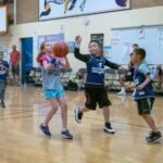 Happy Easter Young players competing in a basketball game in an indoor gymnasium. Spectators watch from the sidelines during the match.