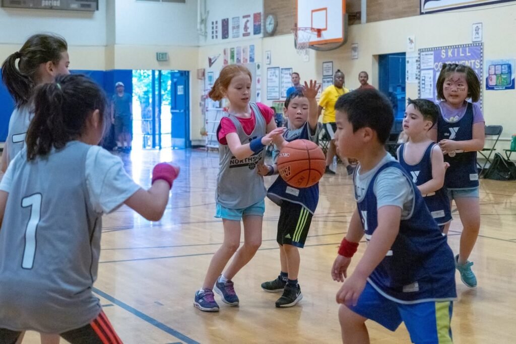 A group of children playing basketball inside a school gymnasium.