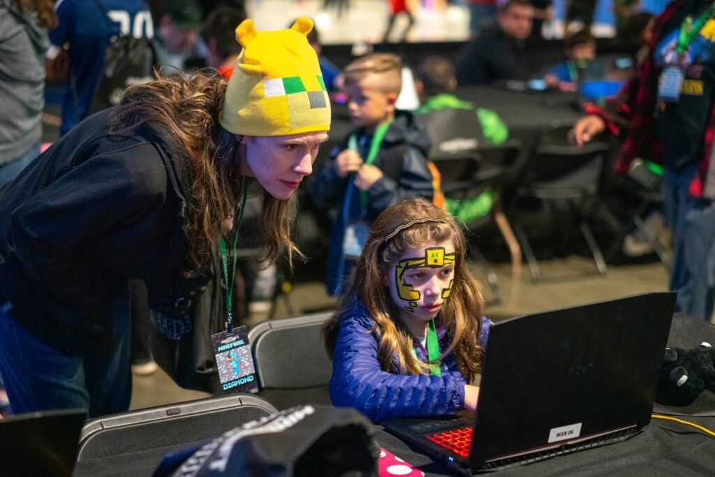 Attendees engage with laptops at a tech event, showcasing youth innovation.