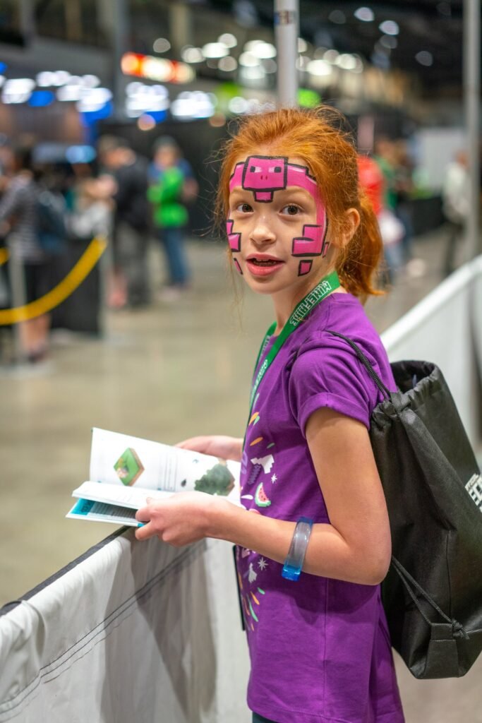 A person with Minecraft-style face paint wearing a purple shirt.