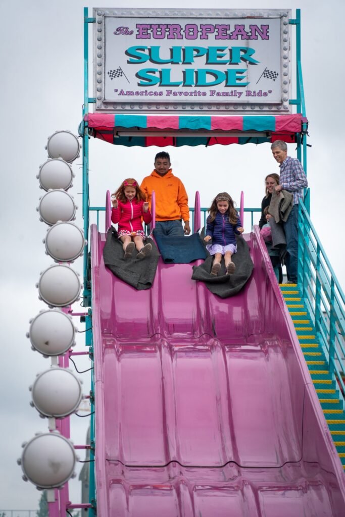 A group of people preparing to go down the pink European Super Slide at an amusement park.