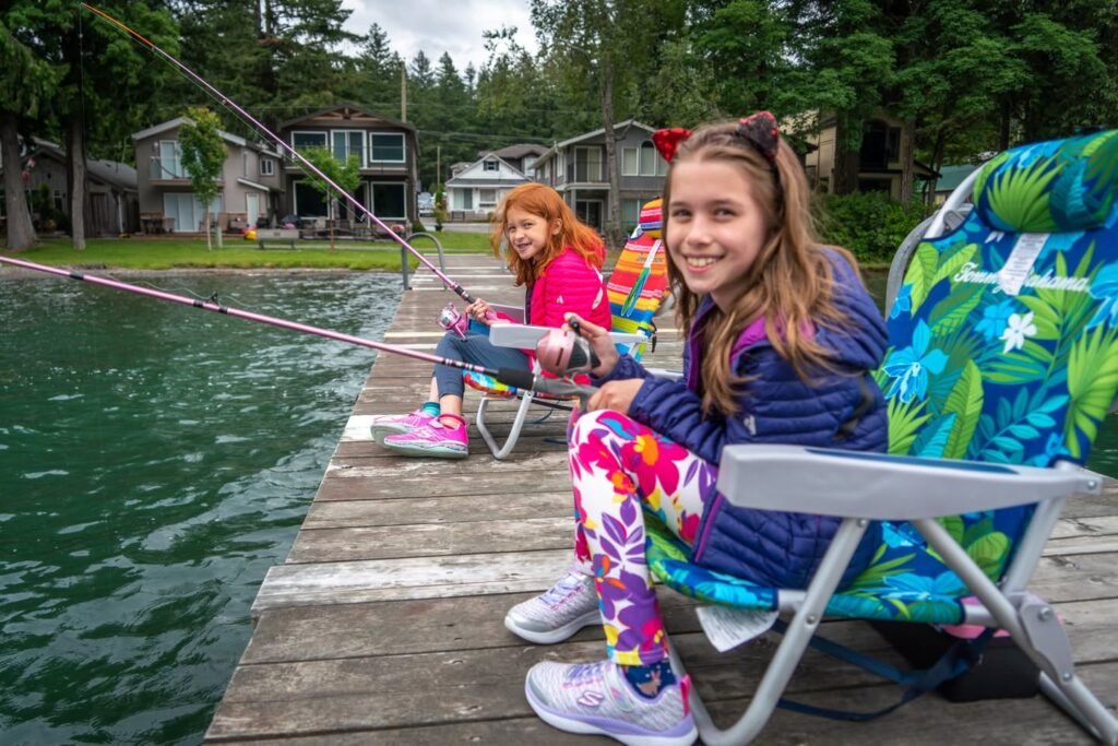 Girls in colorful outfits enjoy a day of fishing from a wooden dock.