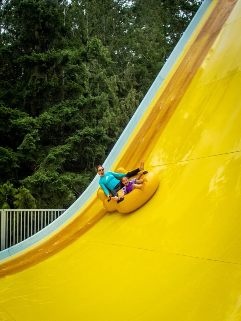 A person sliding down a bright yellow water slide in an inflatable tube.