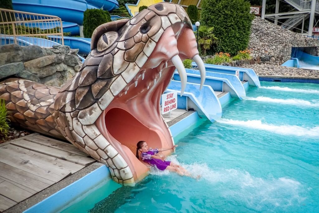 Guest sliding down the giant snake-themed water slide into the river at Great Wolf Lodge. The whimsical design features a large snake head with open jaws.