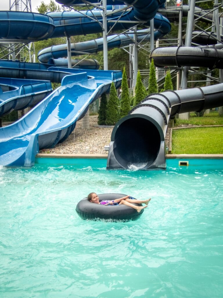 A person floats on an inner tube in a lazy river surrounded by water slides.
