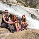 General Sherman A family relaxes on smooth boulders while a waterfall tumbles over the rocks behind them.