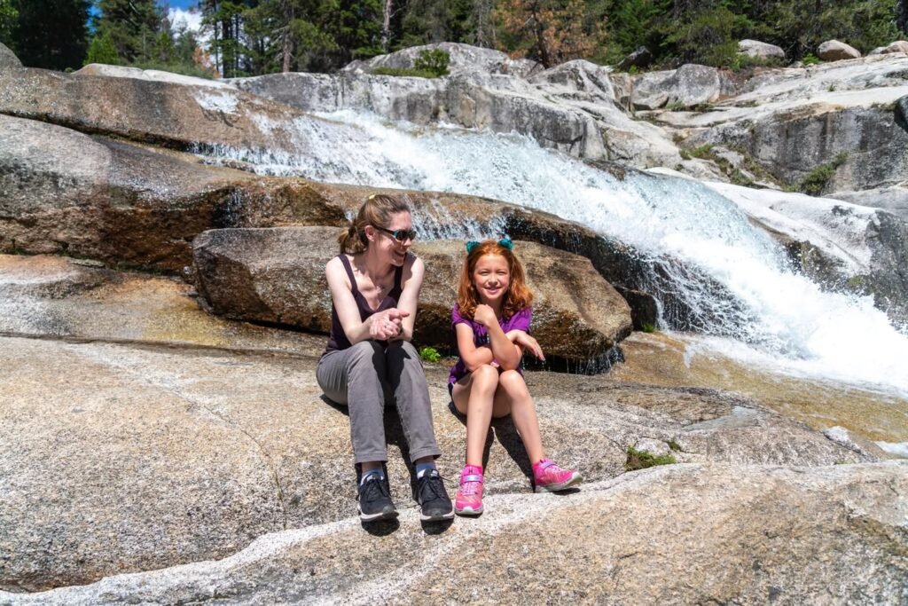 Two children sitting by a rocky stream in the Pacific Northwest, enjoying a family outing.