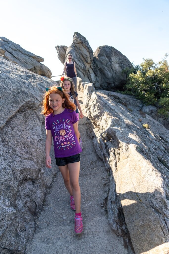 Group of people hiking a rocky mountain trail with rugged stone formations and sparse vegetation.
