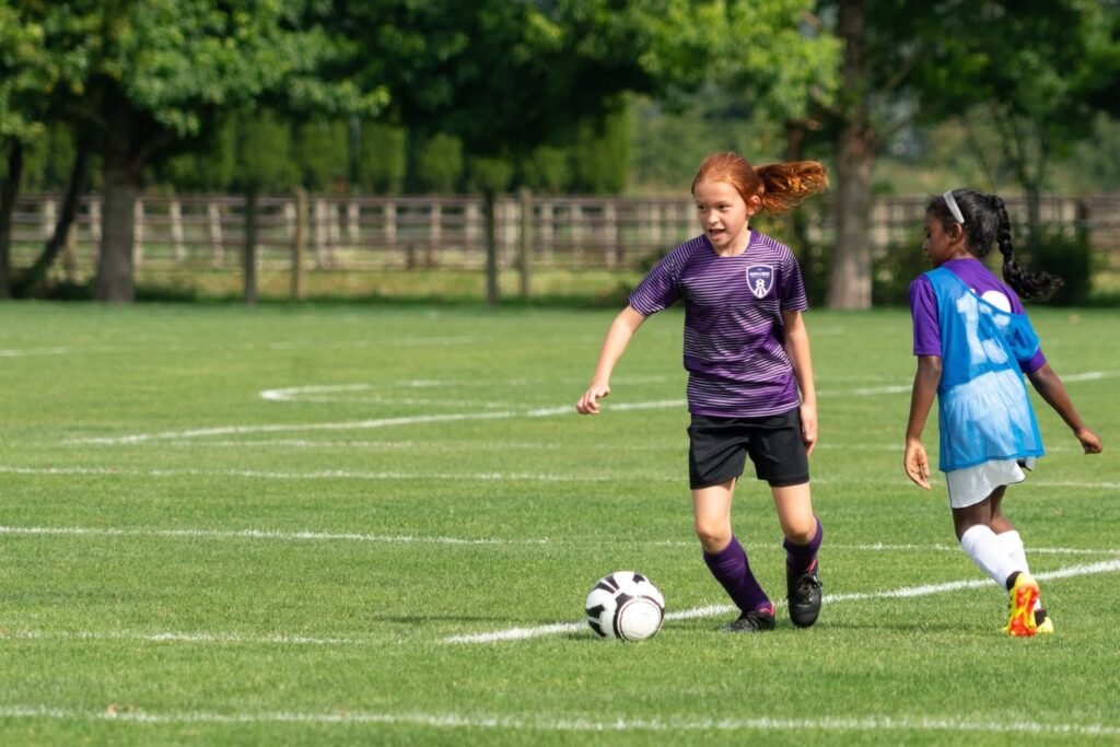 Two players competing for the ball during a sunny outdoor soccer match.
