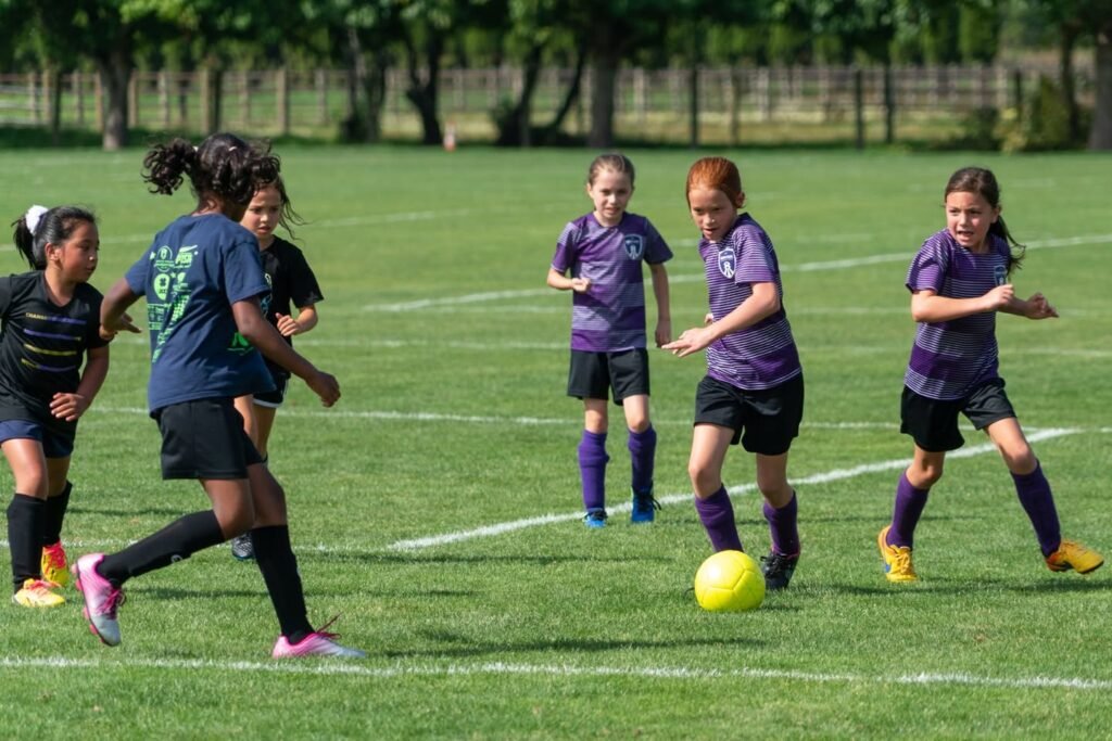 Children playing soccer on a well-maintained field.