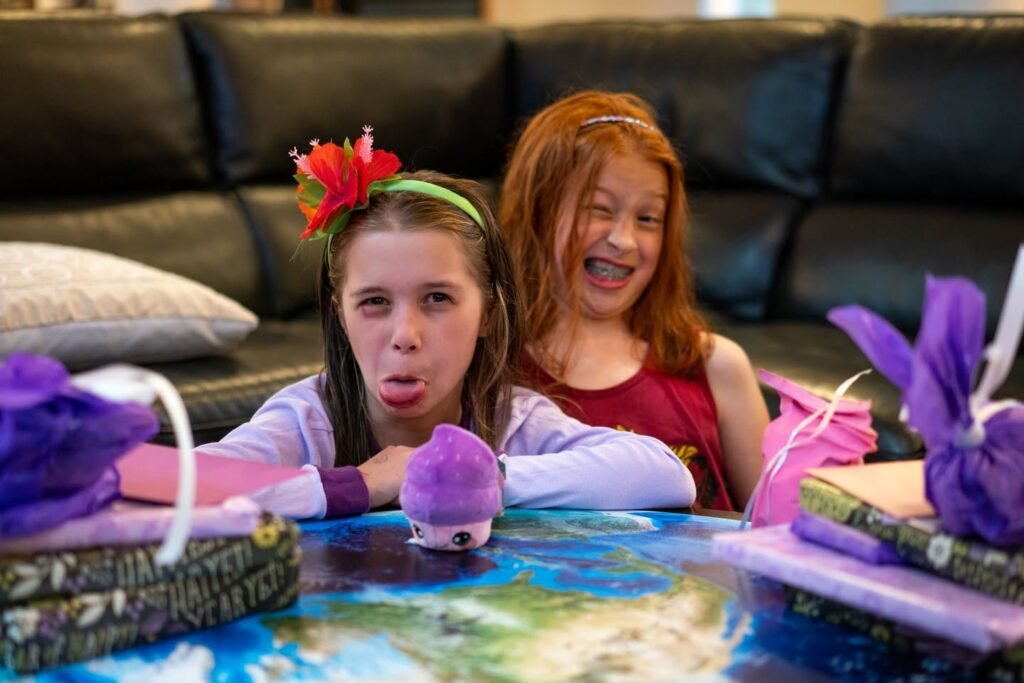 Two young children with excited facial expressions holding a purple plush bunny while surrounded by wrapped Easter presents.