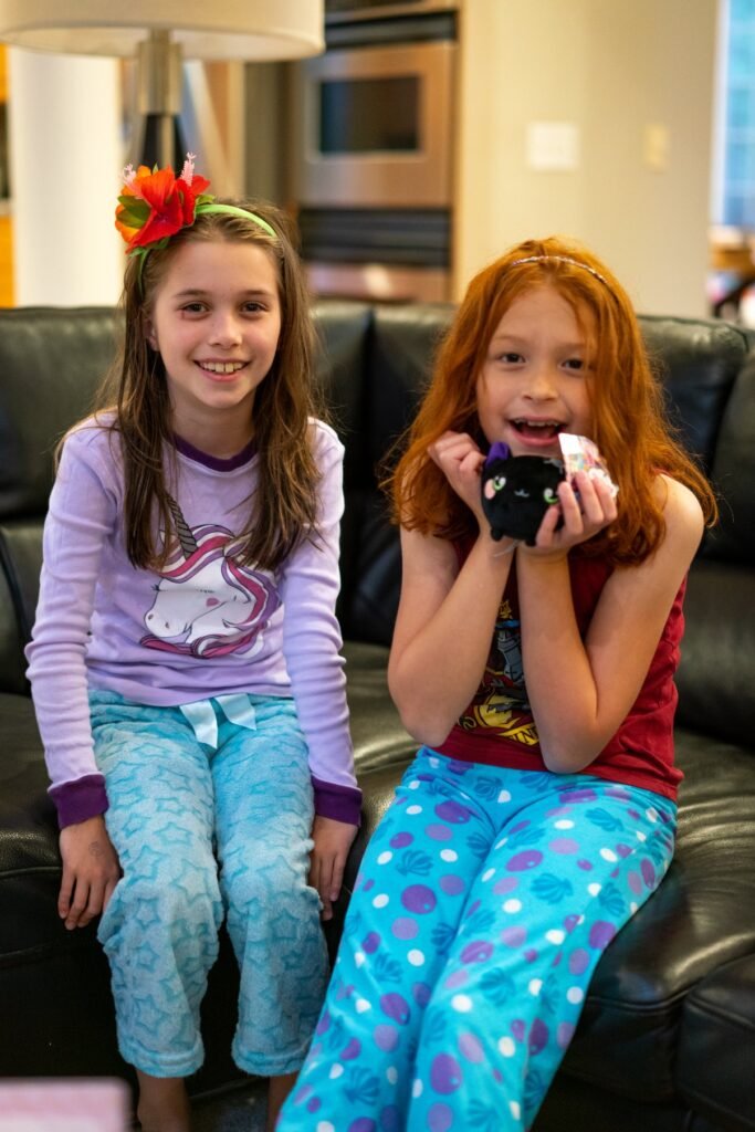 Two children in pajamas sitting on a sofa in a hotel room. One child has a bandage on their face.