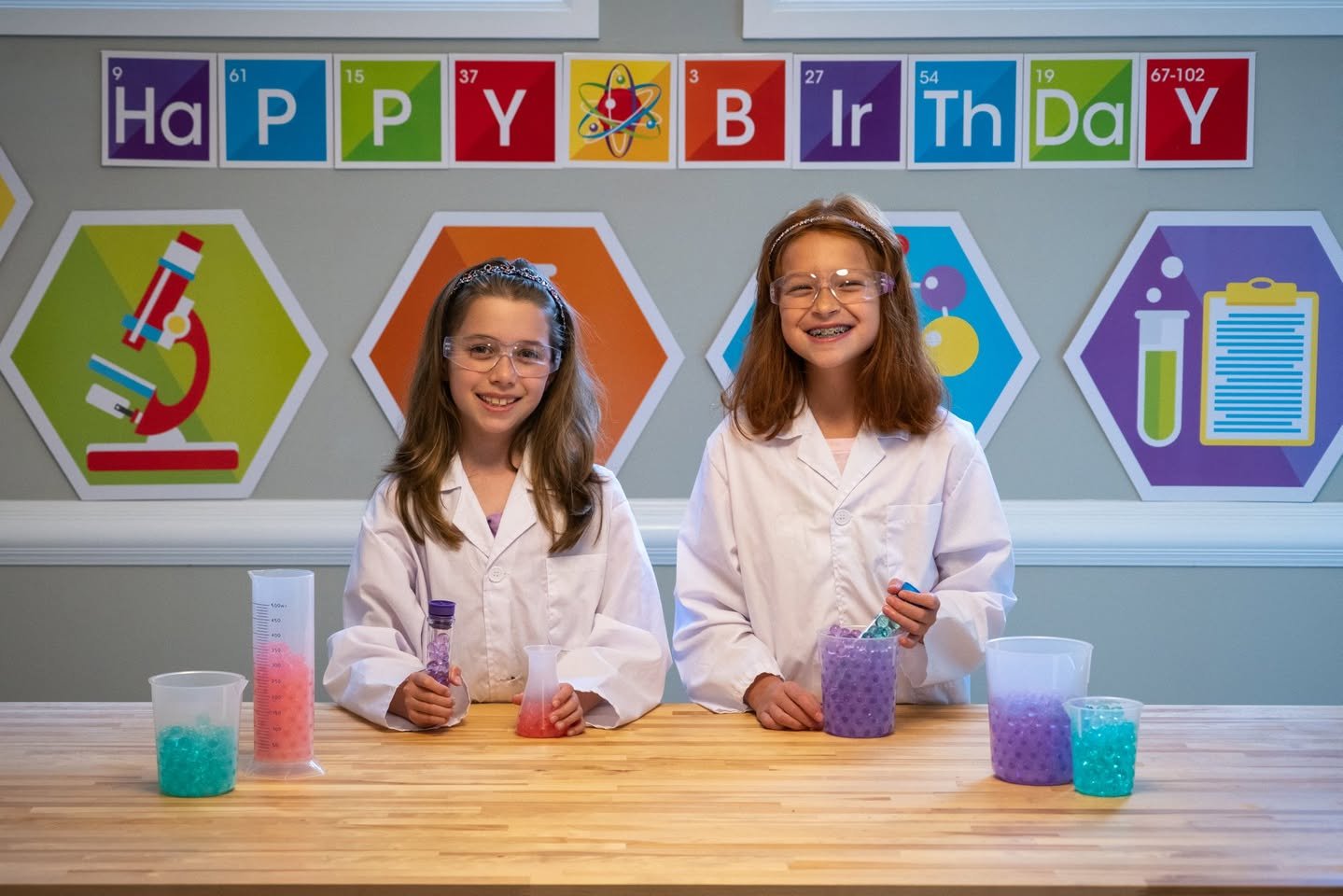 Science Birthday Party Children in lab coats conduct colorful experiments at a Happy Birthday display.