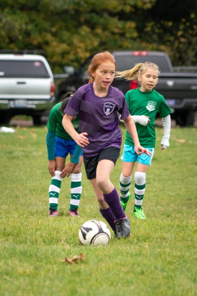 Young players competing for the ball during a soccer game on a grassy field.