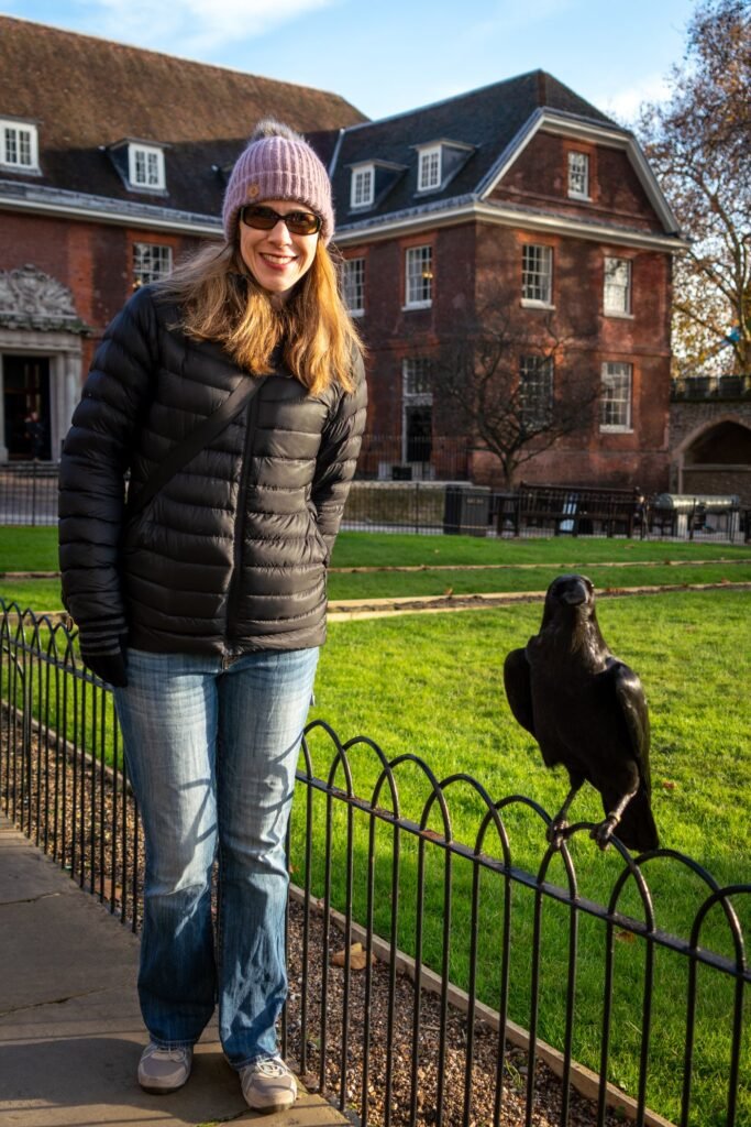 A traveler poses with a statue near a historic red brick building in Plymouth, Massachusetts.