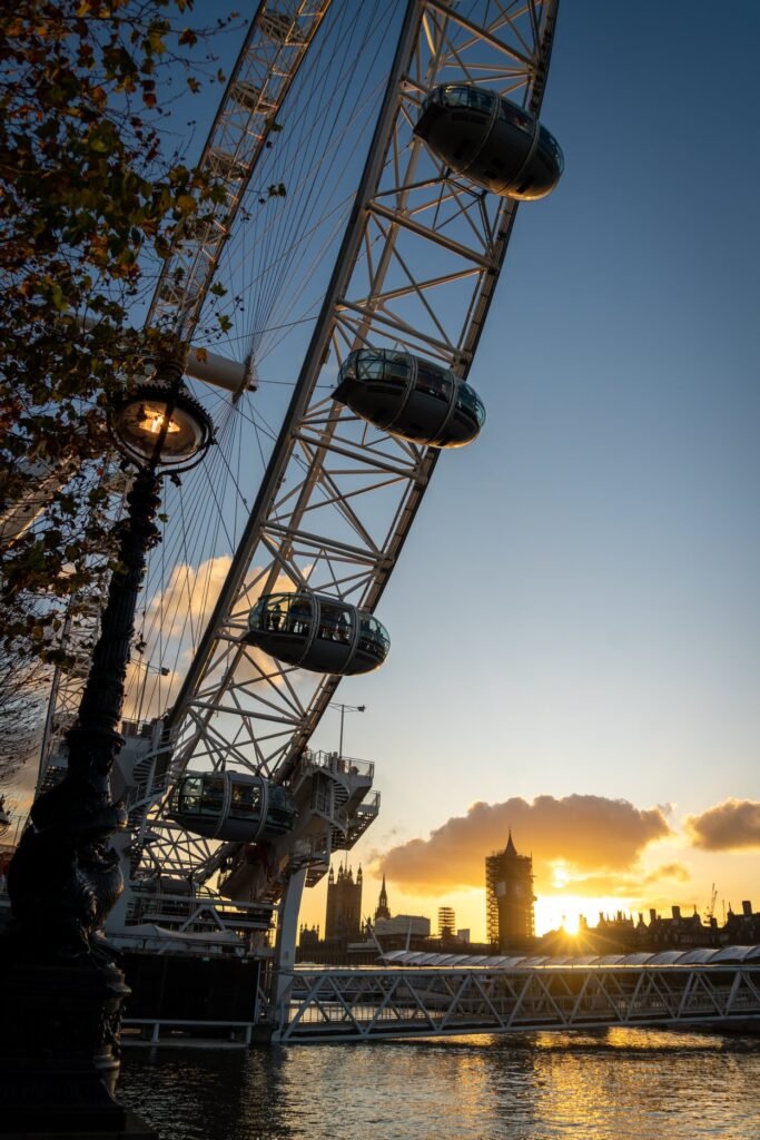 A scenic view of the London Eye at sunset with city silhouettes in the background.
