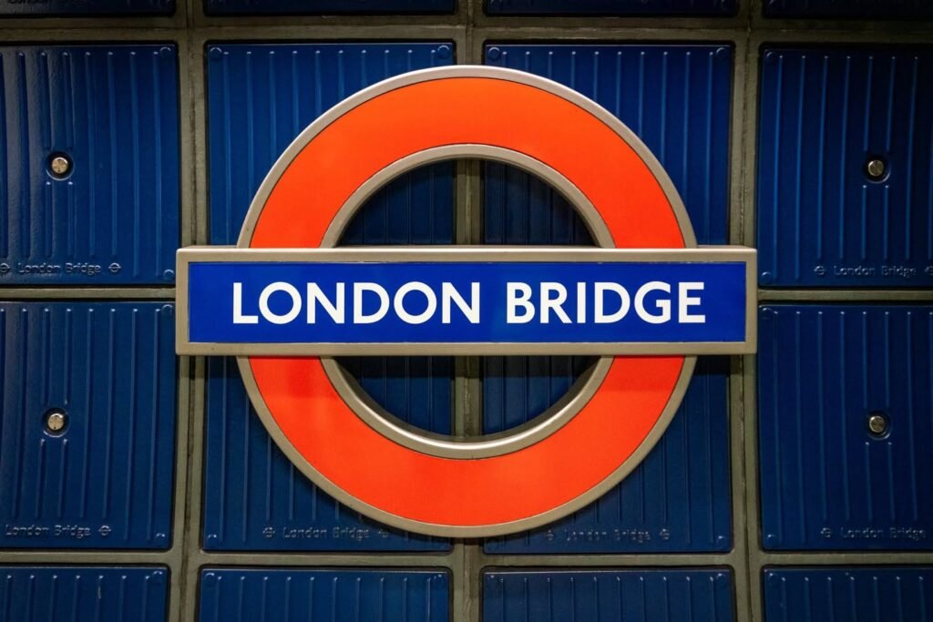 The iconic red roundel and blue text of the London Bridge Underground station sign set against a deep blue tiled wall.