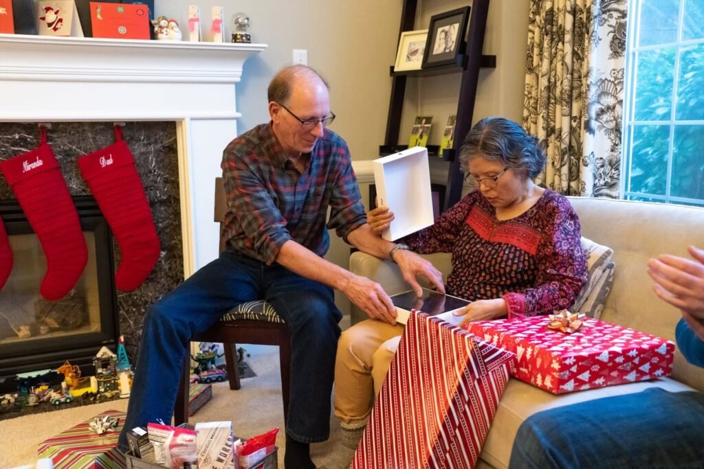 Group exchanging gifts near a fireplace with red stockings during the holiday season.
