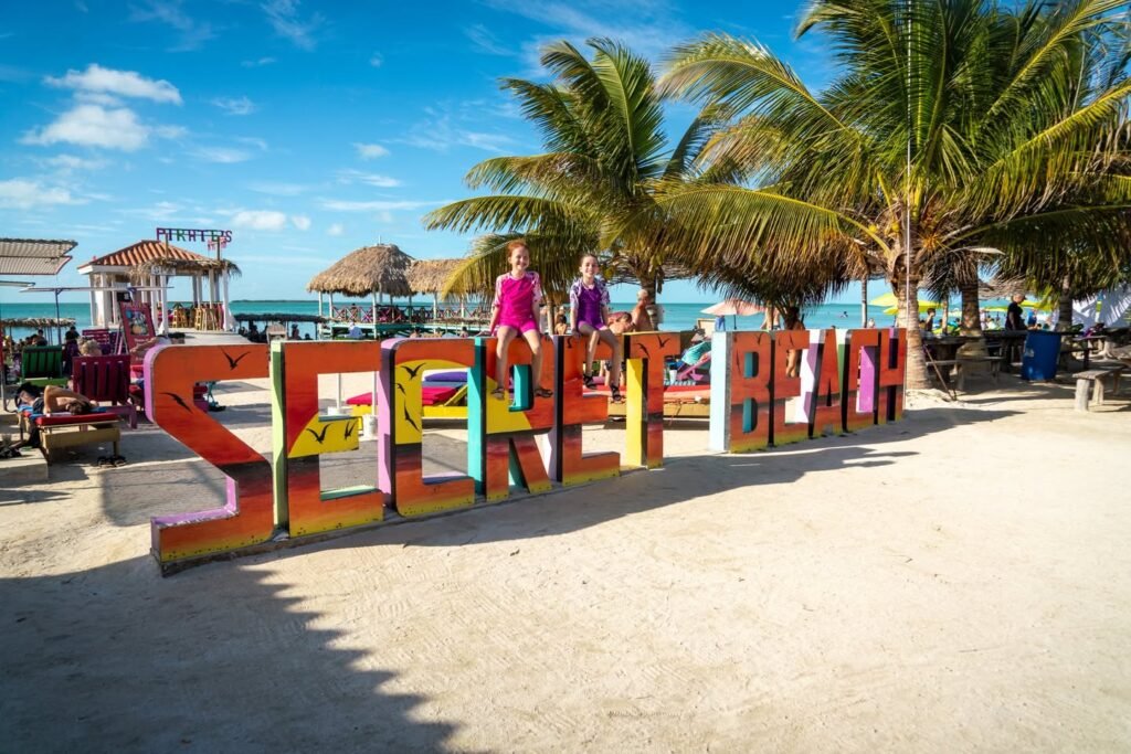 A brightly painted beach sign with palm trees and ocean views at a tropical destination.
