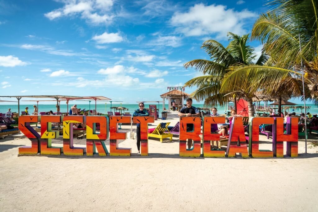 A photo opportunity and panoramic view of the 'Hidden Beach' sign at Costa del Sol hotel in Haad Rin, Thailand, with palm trees and a pool area.
