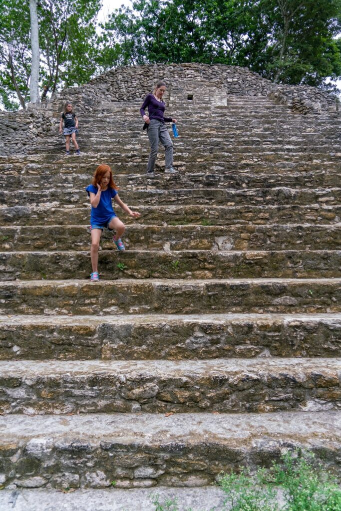 A group climbing a long flight of stone steps at an archaeological site. A person in a blue outfit walks down the ancient stone stairs.