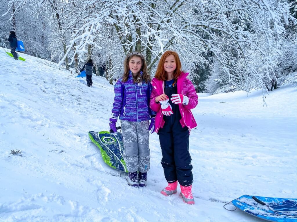 Two visitors enjoy a snowy day in the Pacific Northwest with sledding equipment.