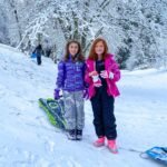 Two visitors enjoy a snowy day in the Pacific Northwest with sledding equipment.