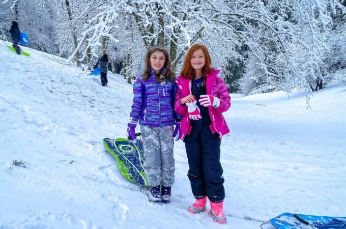 Two visitors enjoy a snowy day in the Pacific Northwest with sledding equipment.