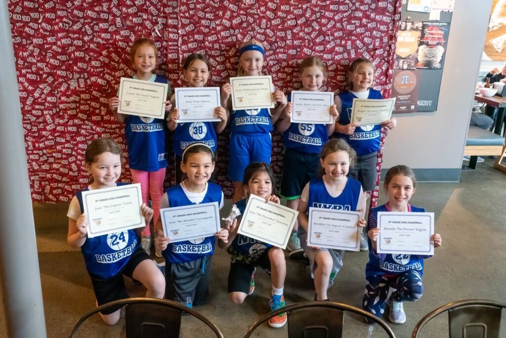 A youth soccer team holding certificates in blue uniforms after a celebration.