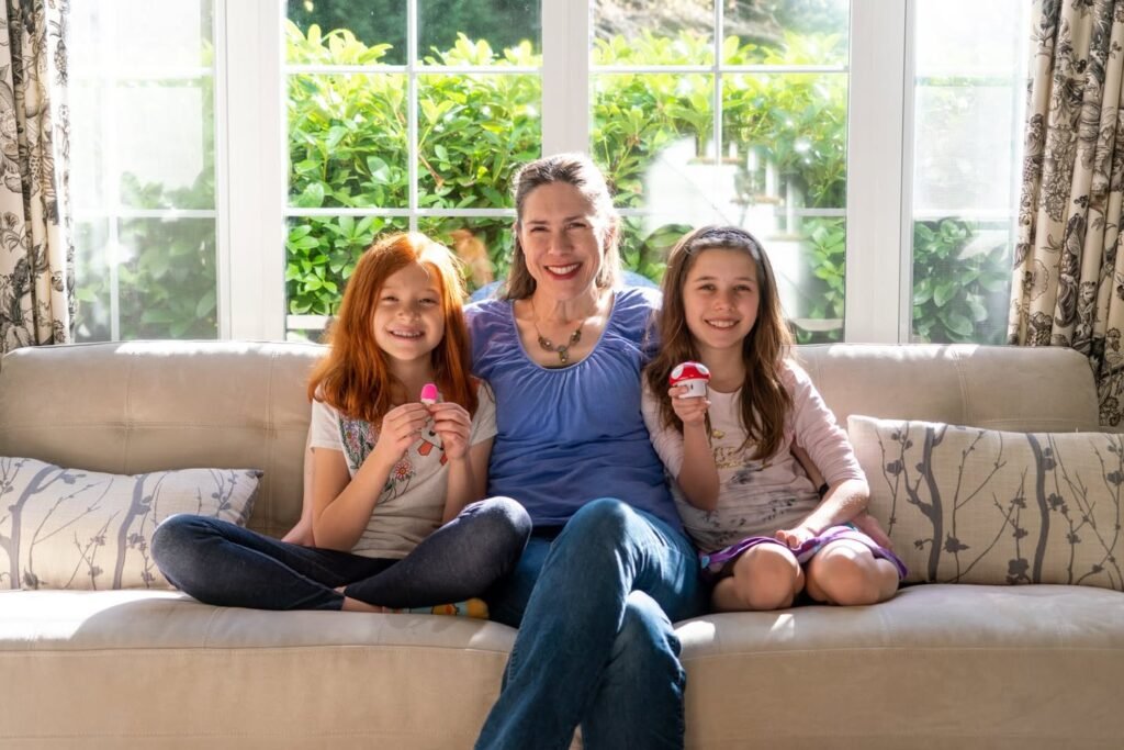 A family of three enjoys ice cream while sitting together on a sunlit couch. This warm family moment captures a happy time at home.