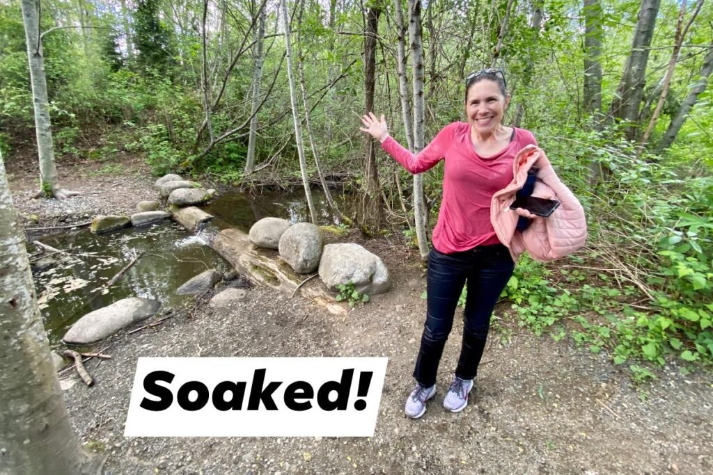 A traveler standing by a muddy forest stream in the rain.