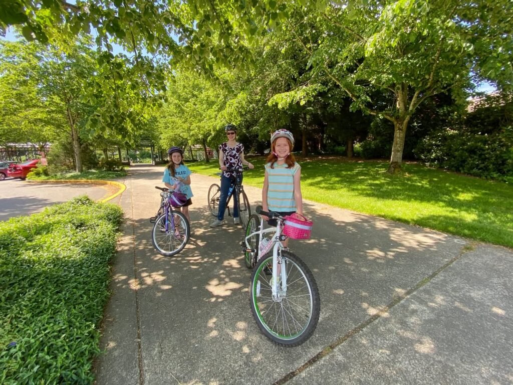 Children learn to ride bikes on a sunny day at a local park.