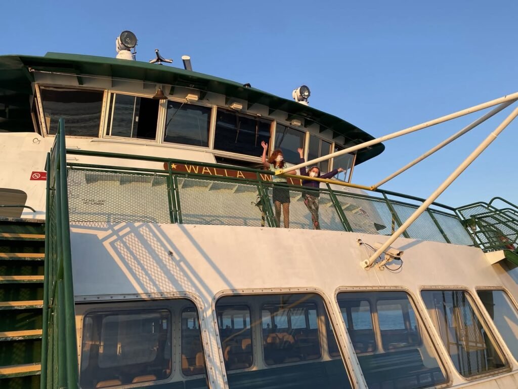 View of a ferry deck with passengers enjoying the golden hour against a clear blue sky.