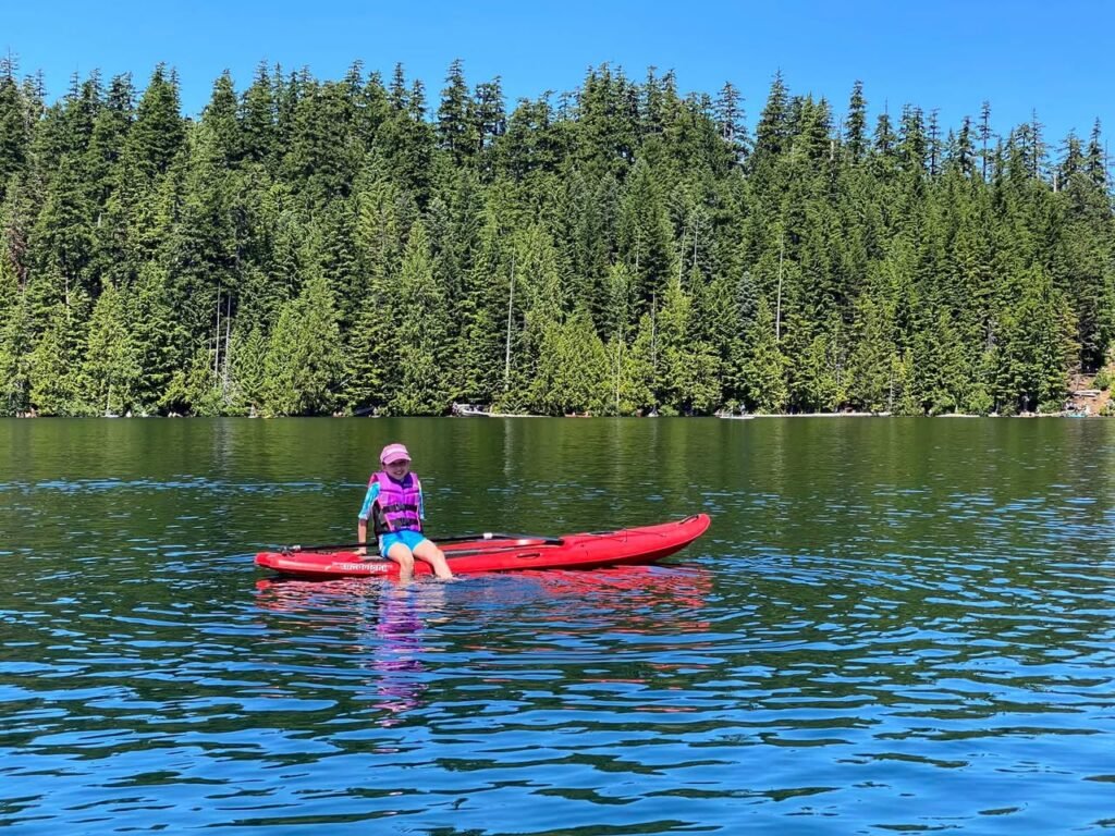 A person in a red kayak paddles on a peaceful lake surrounded by evergreen trees. Various angles capture the serene water and forested shoreline.